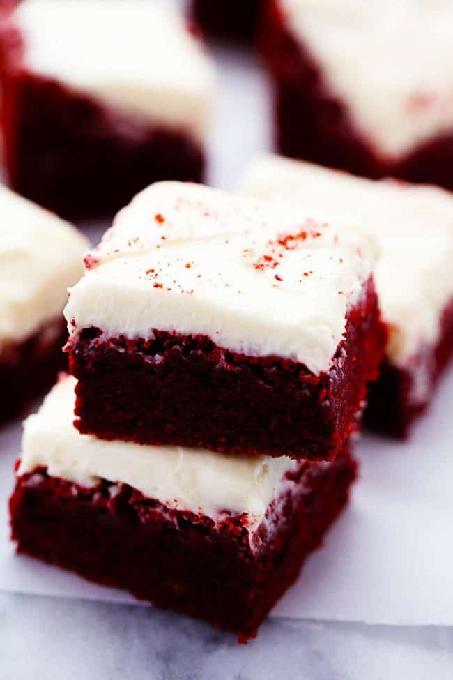 Red velvet brownies stacked on top of each other on the parchment paper.