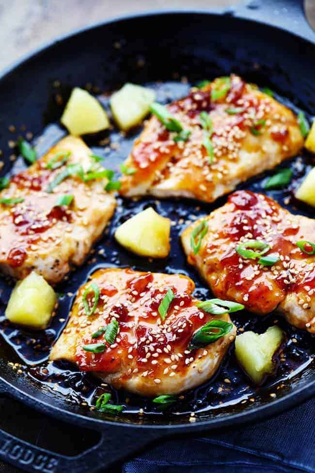 Teriyaki Chicken in black bowl with pineapple and onion.