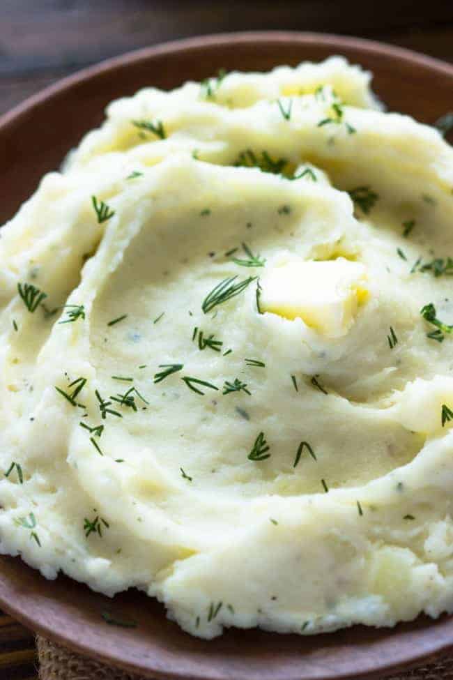 Close up photo of Slow Cooker Ranch Mashed Potatoes in a brown bowl. 
