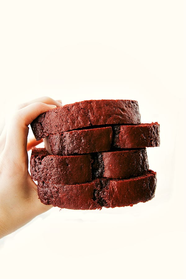 Four slices of red velvet pound cake with a hand holding them. 