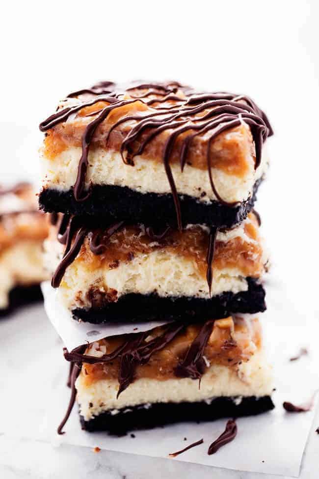 Samoa cheesecake bar stacked on top of one another with parchment paper in between.