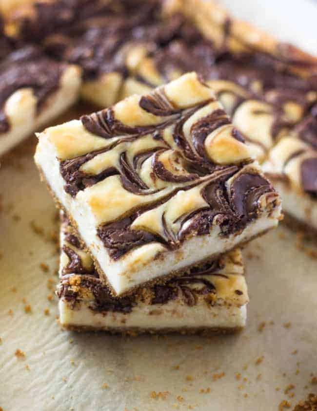 Nutella Swirl Cheesecake Bars stacked on top of one another on a baking sheet.
