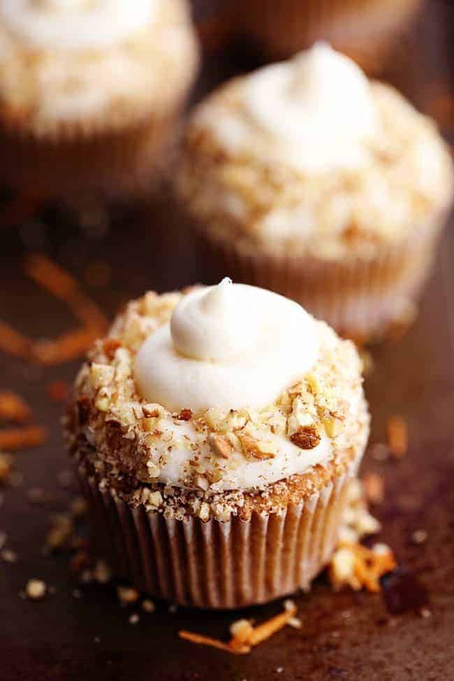 Carrot Cake Cupcakes with White Chocolate Cream Cheese Frosting on a brown countertop. 