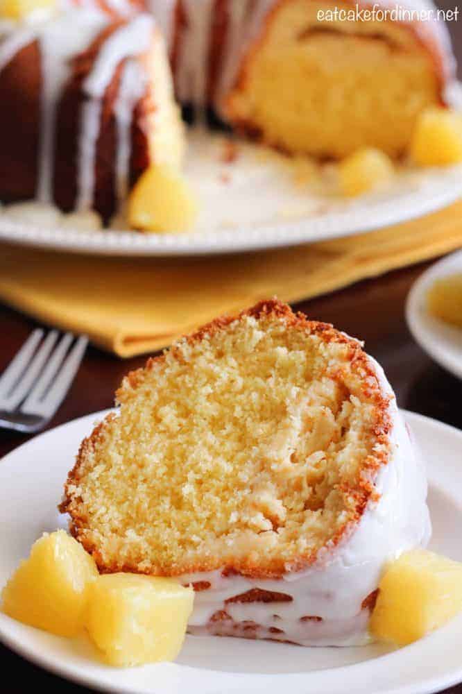 Pineapple Cheesecake Cake on a white plate with pineapple chunks on the side.  