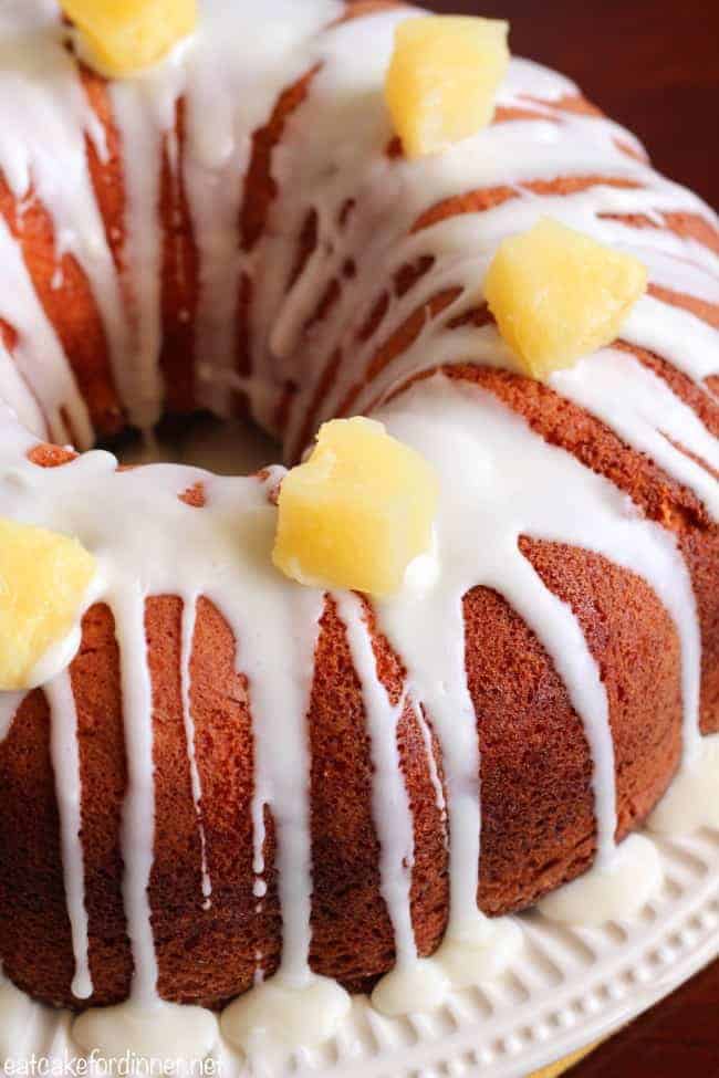 Pineapple Cheesecake Cake on a cake stand with fresh pineapple chunks on top.  