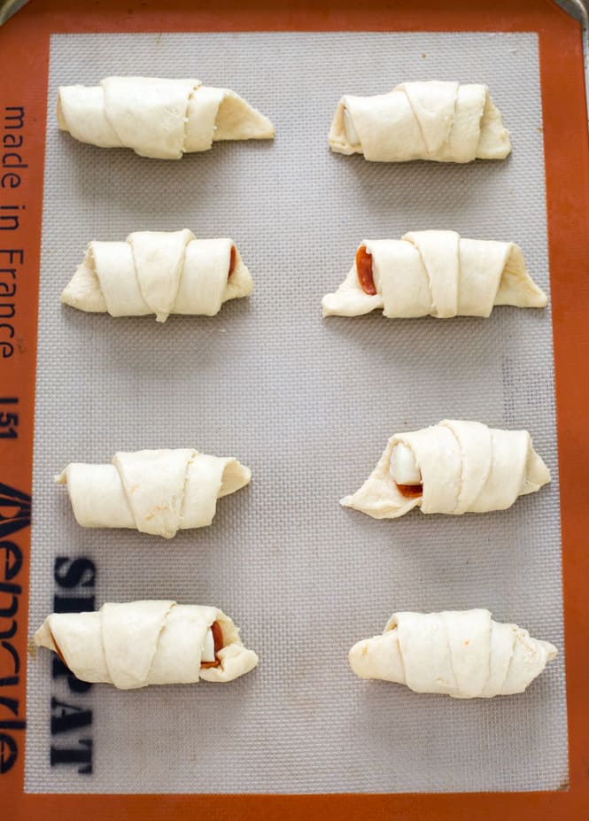 Pizza crescent rolls in rows ready to put in the oven.