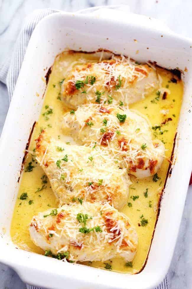 Creamy baked asiago chicken in a white casserole dish. 