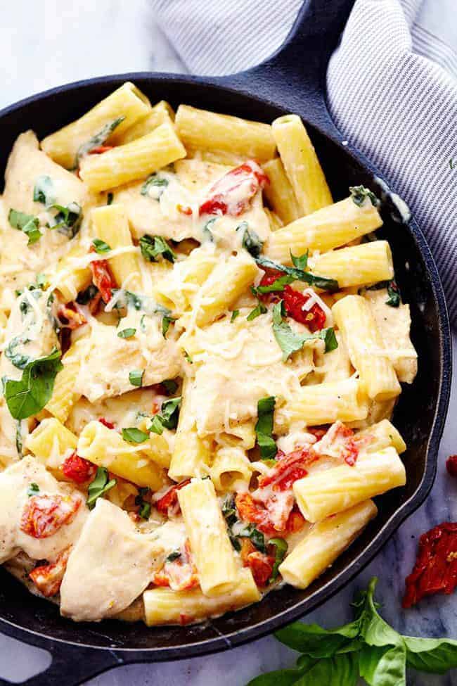 Mozzarella Chicken Pasta with Sun Dried Tomatoes in a black skillet. 