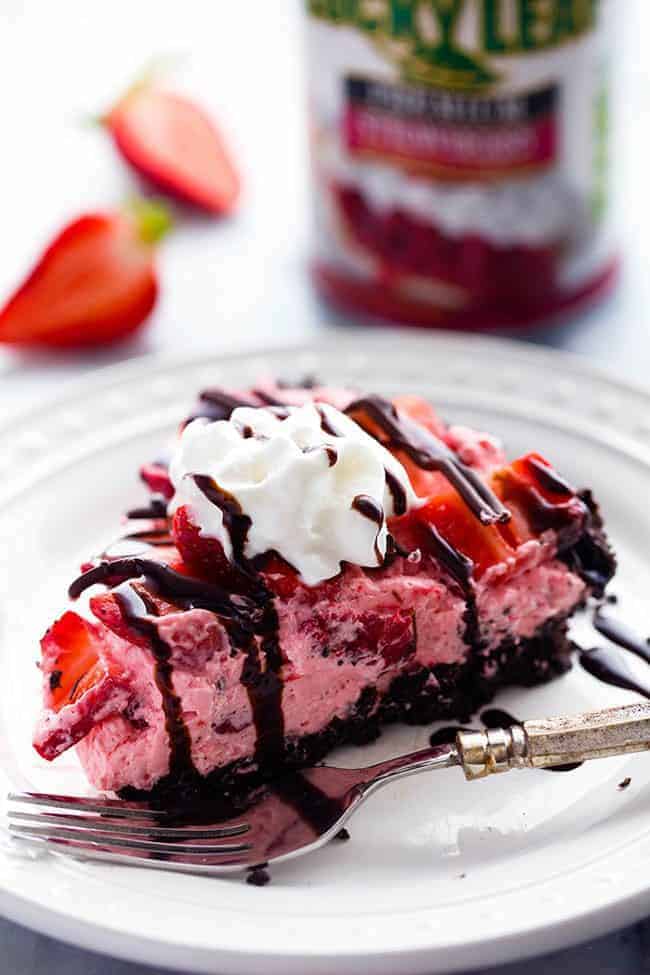 A slice of No Bake Chocolate Strawberries and Cream Pie on a white plate with a metal fork. 