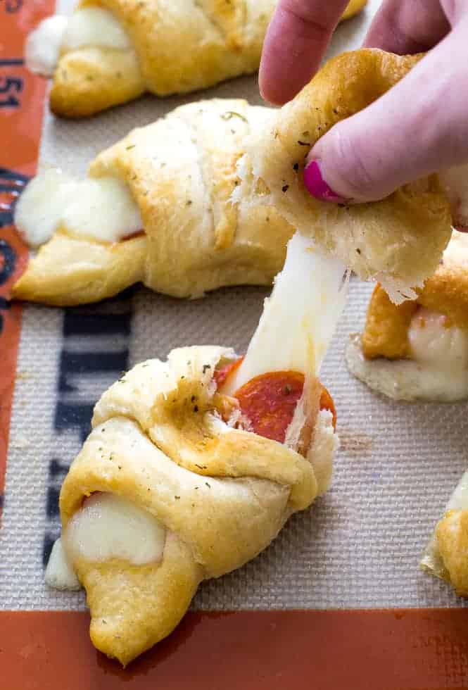 Crescent rolls being pulled apart to show gooey cheese.