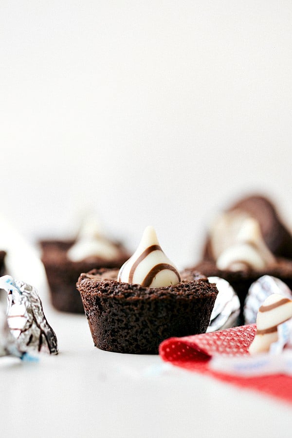 Mit Schokolade gefüllte Mini-Brownie-Häppchen mit Hersey's Hugs oben drauf und auf dem Tisch. 
