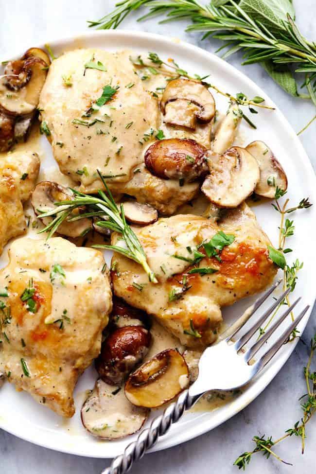 Creamy Garlic Herb Mushroom Chicken on a white plate with a metal fork. 