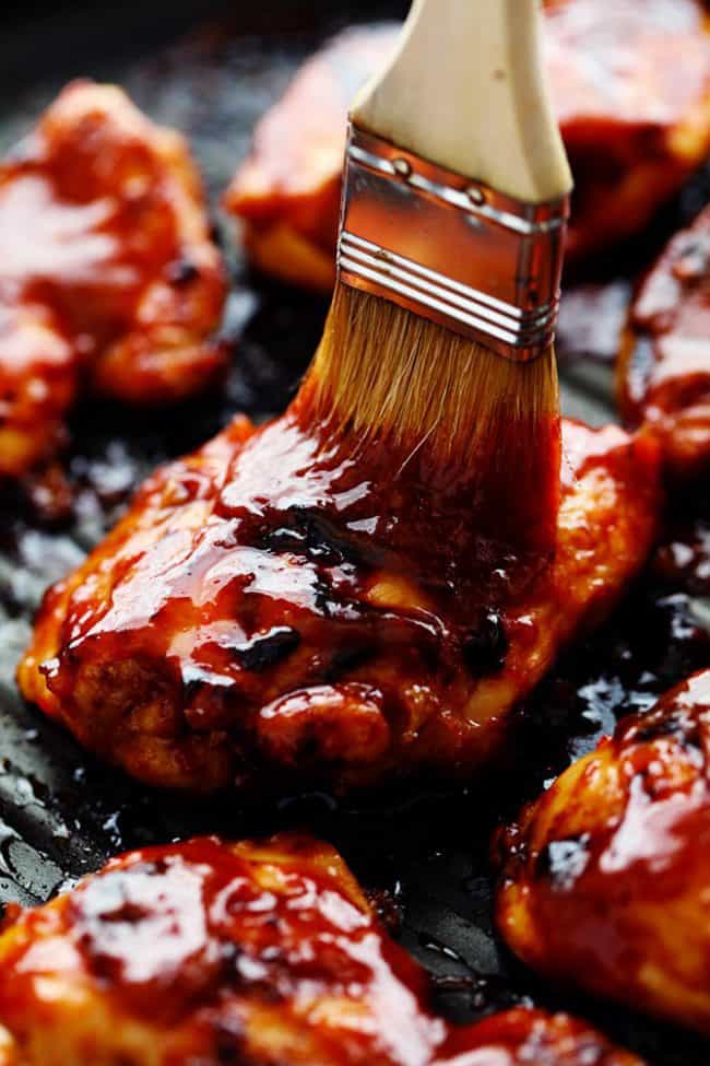 Basting brush applying honey chipotle sauce to the chicken on the grill. 