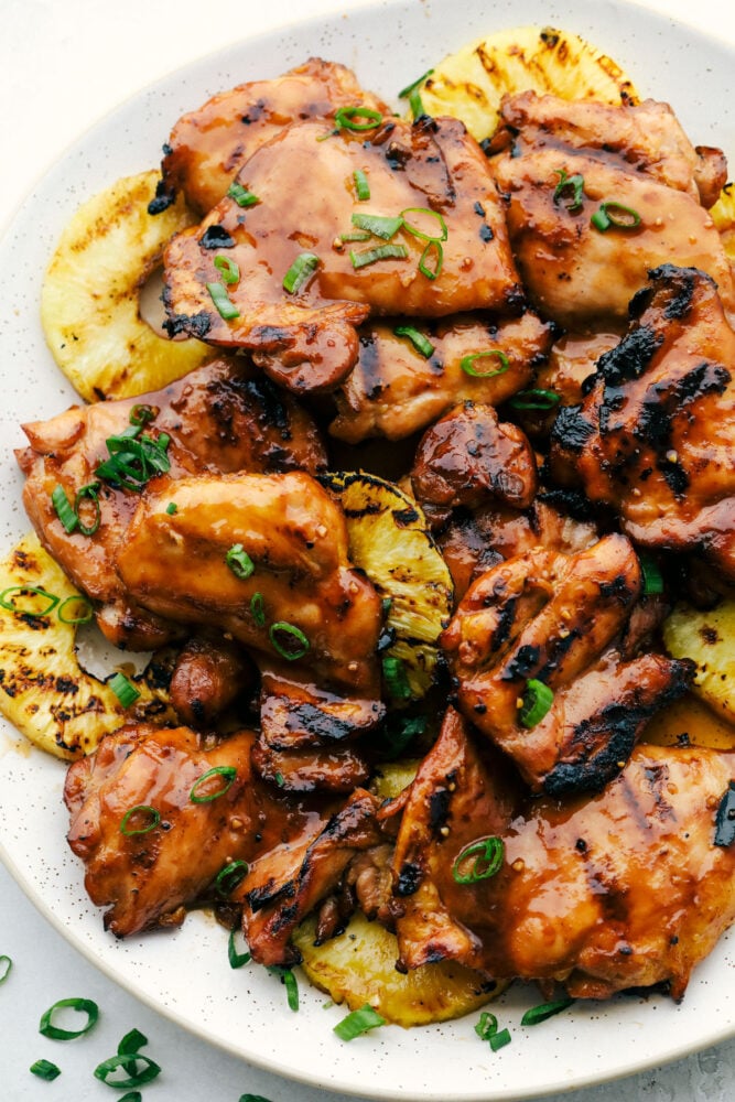 Holi Grilled Chicken On A Plate Of Grilled Pineapple And Garnished With Green Onions. 