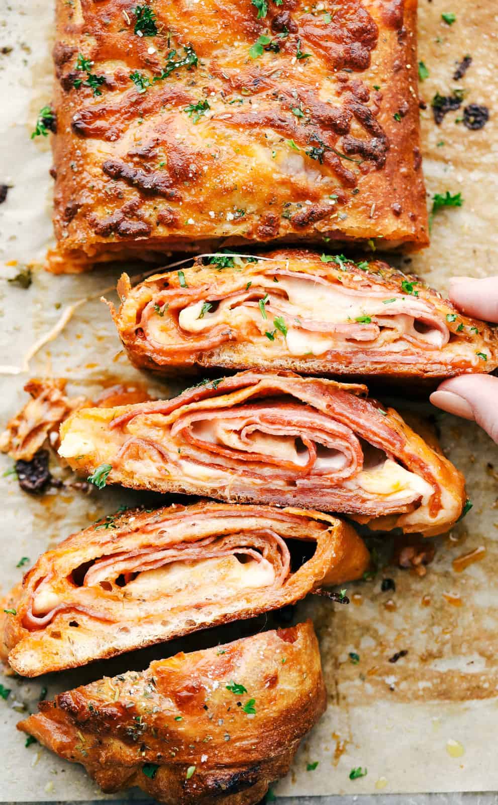 Stromboli cut into slices showing the layers of Italian meat, cheese and baked pizza dough. 