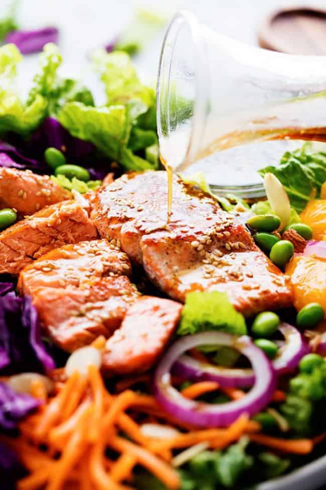 Asian Pan Seared Salmon Salad with dressing being poured over it. 