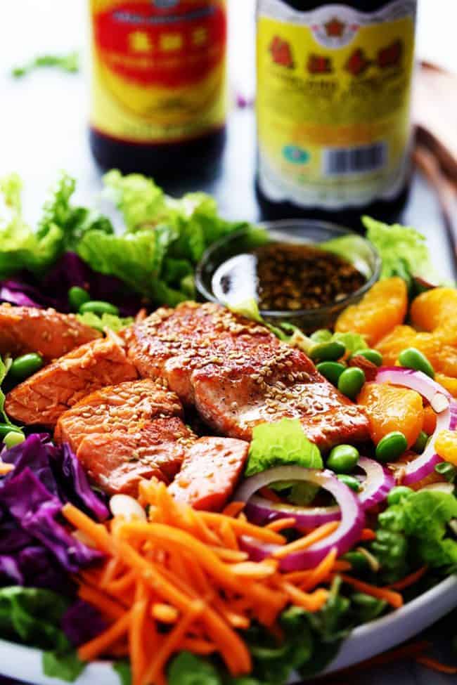 Asian Pan Seared Salmon Salad with two bottles of soy sauce on the side.