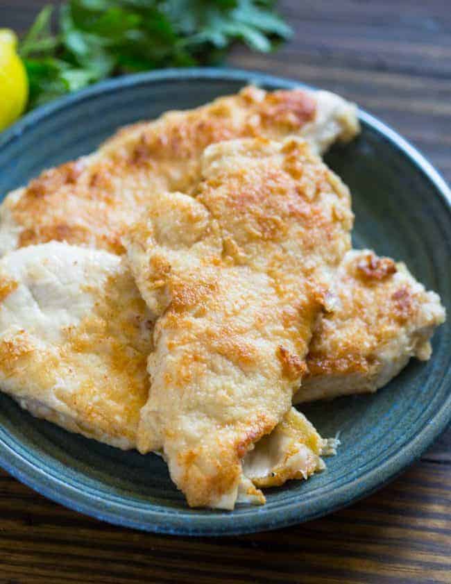 Creamy Lemon Garlic Chicken on a dark blue plate on a wooden table. 