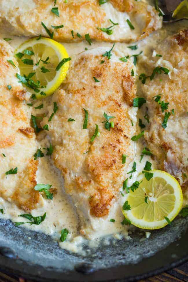 Close up of Creamy Lemon Garlic Chicken on a plate with fresh lemon slices. 