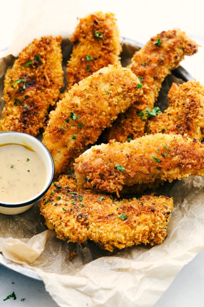 Chicken tenders in a basket with honey mustard sauce. 