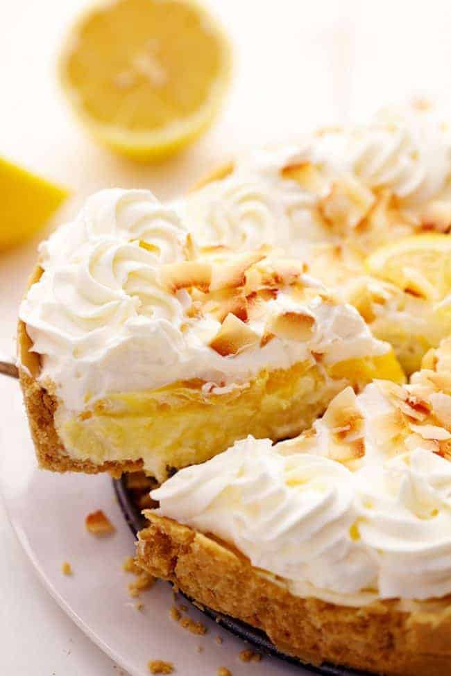 No Bake Lemon Macaroon Cheesecake with a slice being removed and lemons in the background.  