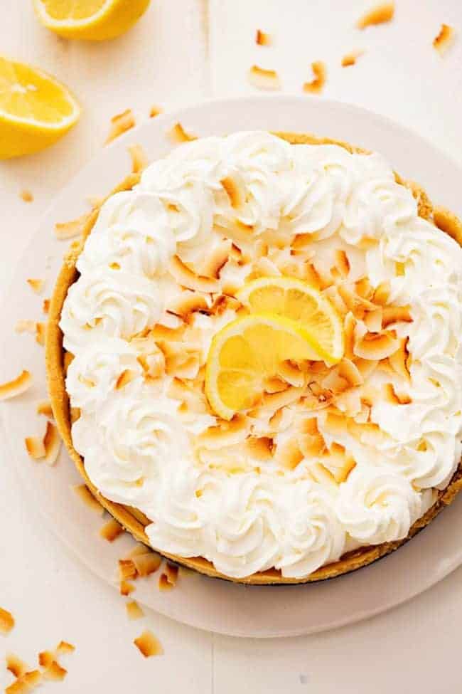 No Bake Lemon Macaroon Cheesecake on a white plate with fresh lemons on the side.  