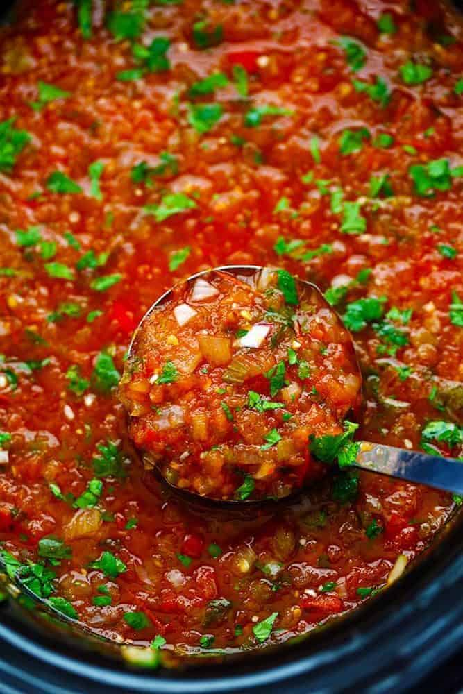 Restaurant Style Garden Salsa in a slow cooker with a ladle removing some. 