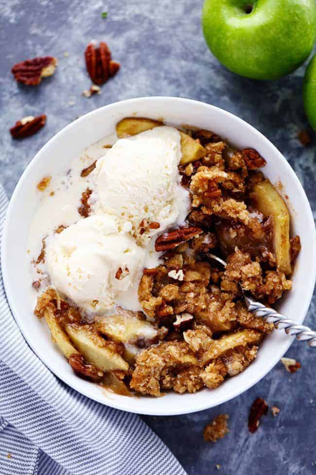Overhead photo of Apple Pecan Crisp in a white bowl with vanilla ice cream. 