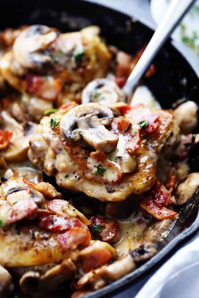 Creamy Bacon Mushroom Thyme Chicken in a black skillet with a metal spoon. 