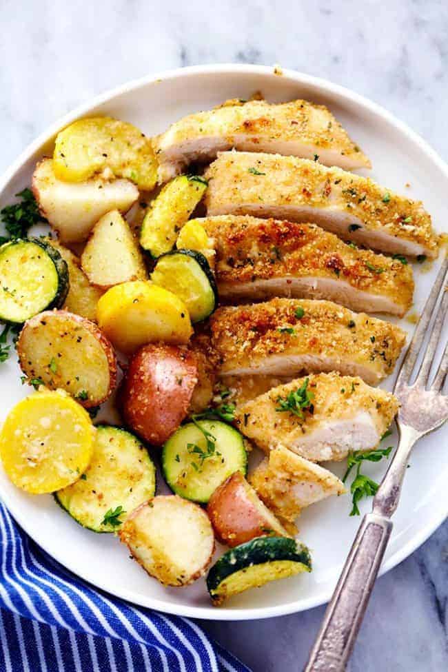 One Pan Crispy Parmesan Garlic Chicken with Vegetables on a white plate with a metal fork. 