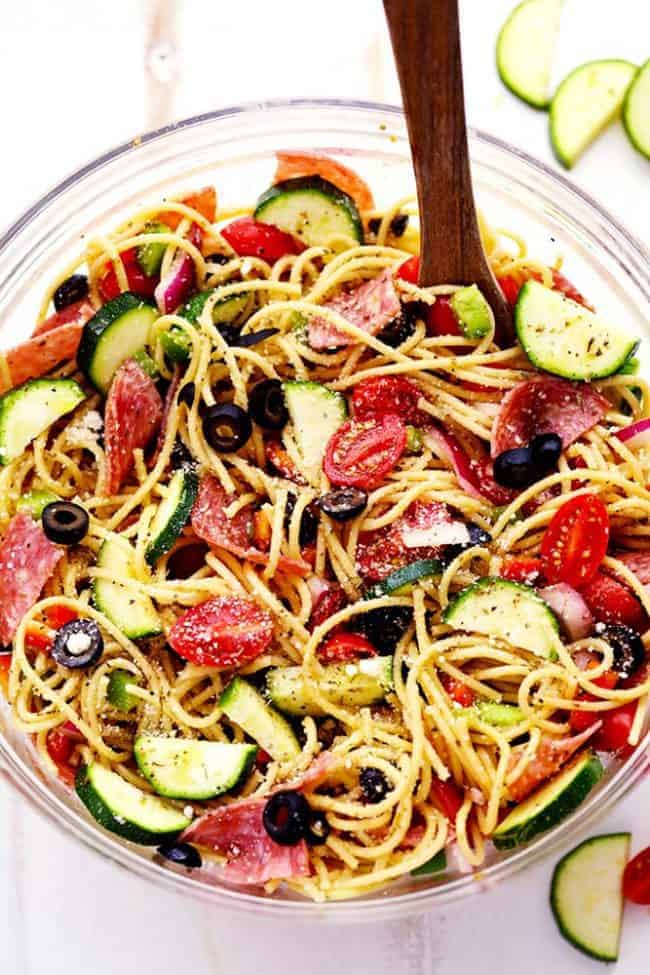 Italian Spaghetti Salad in a clear bowl and wooden spoon. 