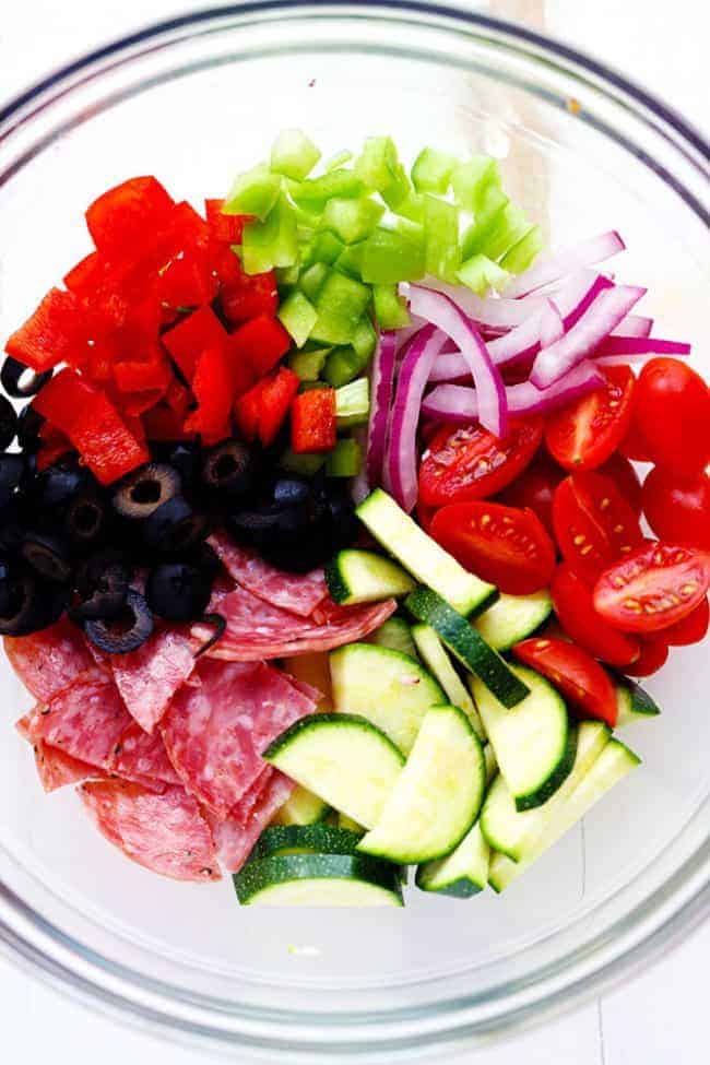 Ingredients for Italian Spaghetti Salad in a clear bowl. 