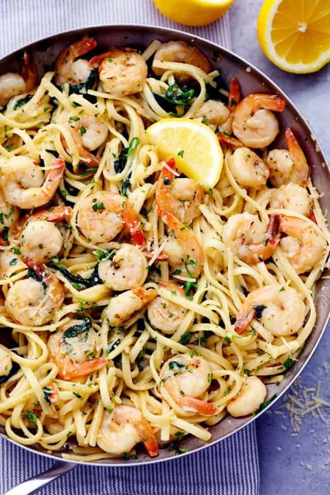 Lemon Garlic Parmesan Shrimp Pasta in a skillet with fresh lemons on the side. 