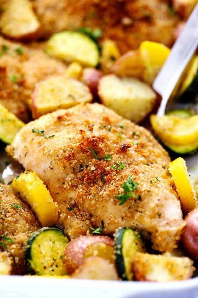 Close up of One Pan Crispy Parmesan Garlic Chicken with Vegetables with a metal spoon. 