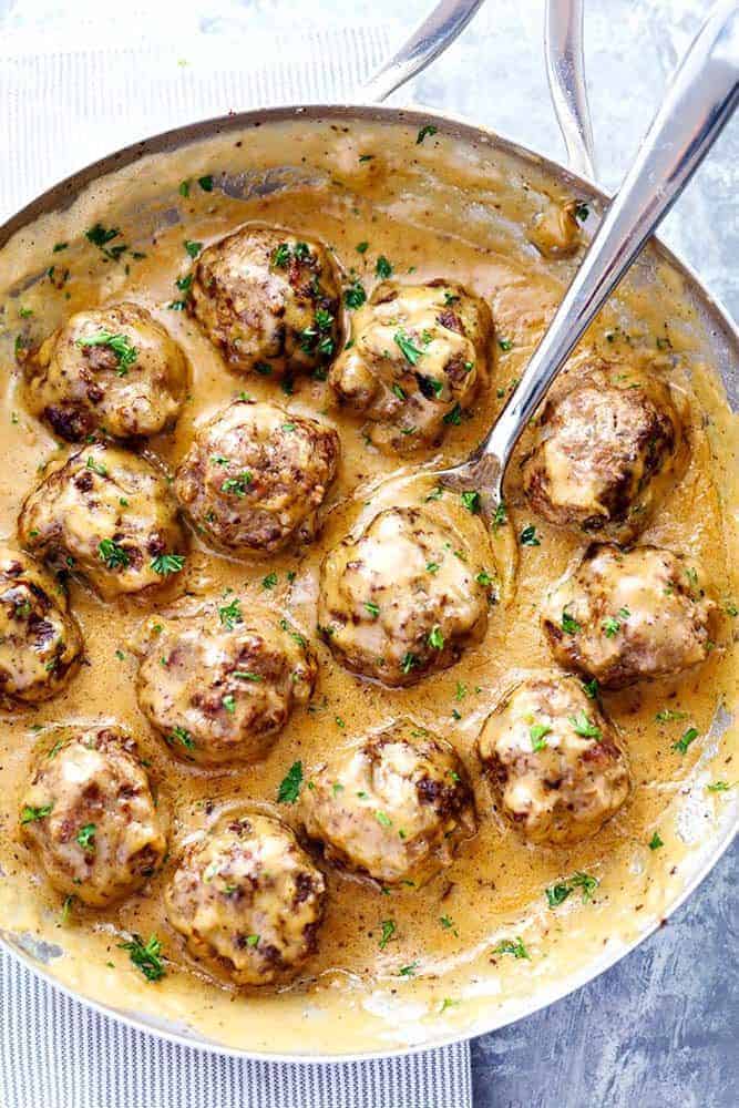 Swedish Meatballs in a frying pan with a metal spoon. 