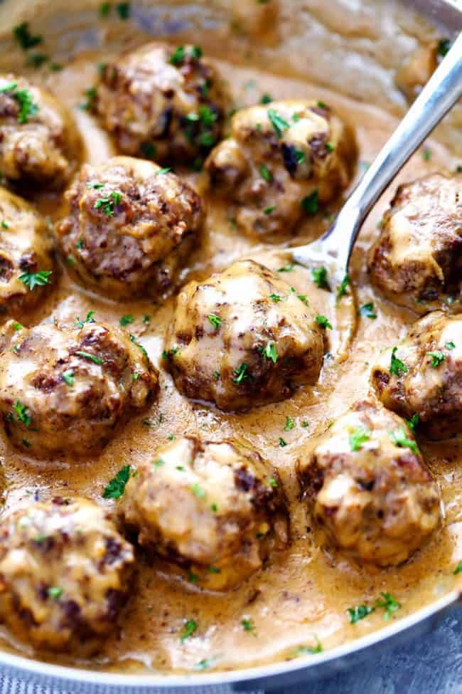 Close up of Swedish Meatballs in a frying pan with a metal spoon. 