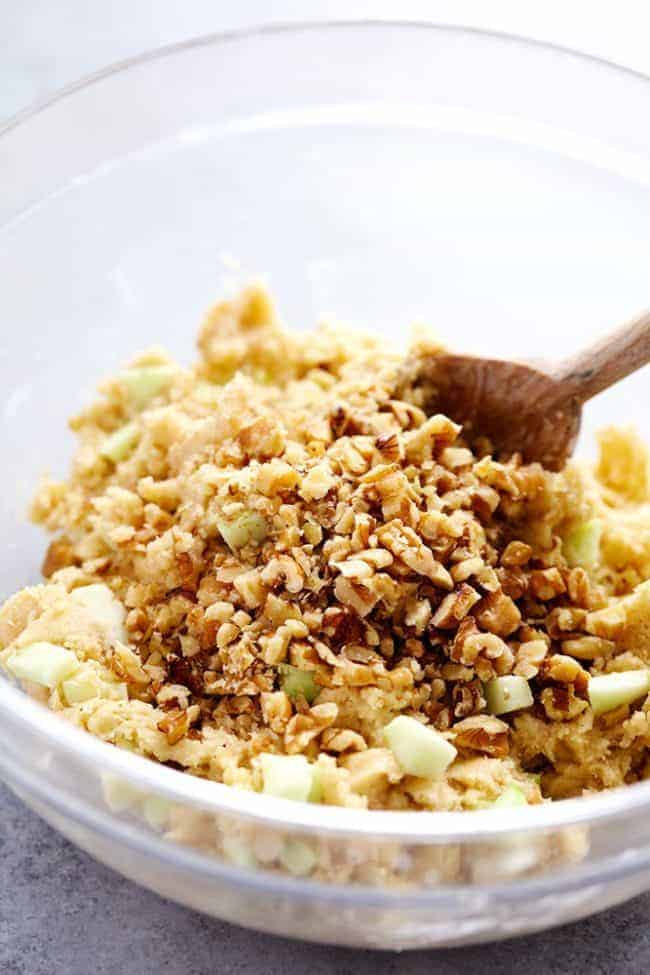 Apple cream cheese, muffin ingredients in a glass bowl being stirred together with the wooden spoon.