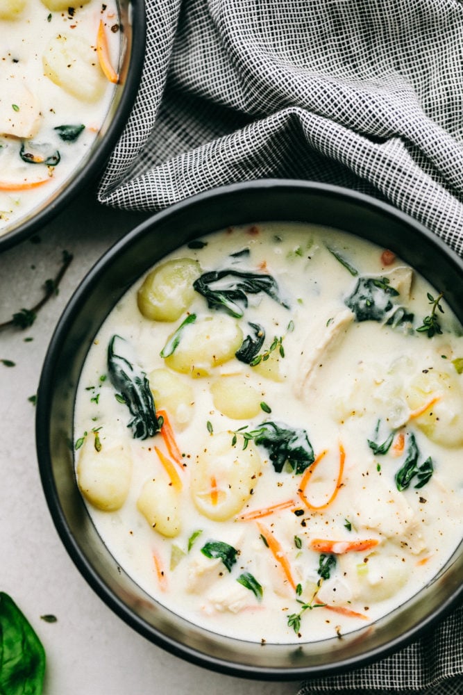 Chicken gnocchi soup in a black bowl. 