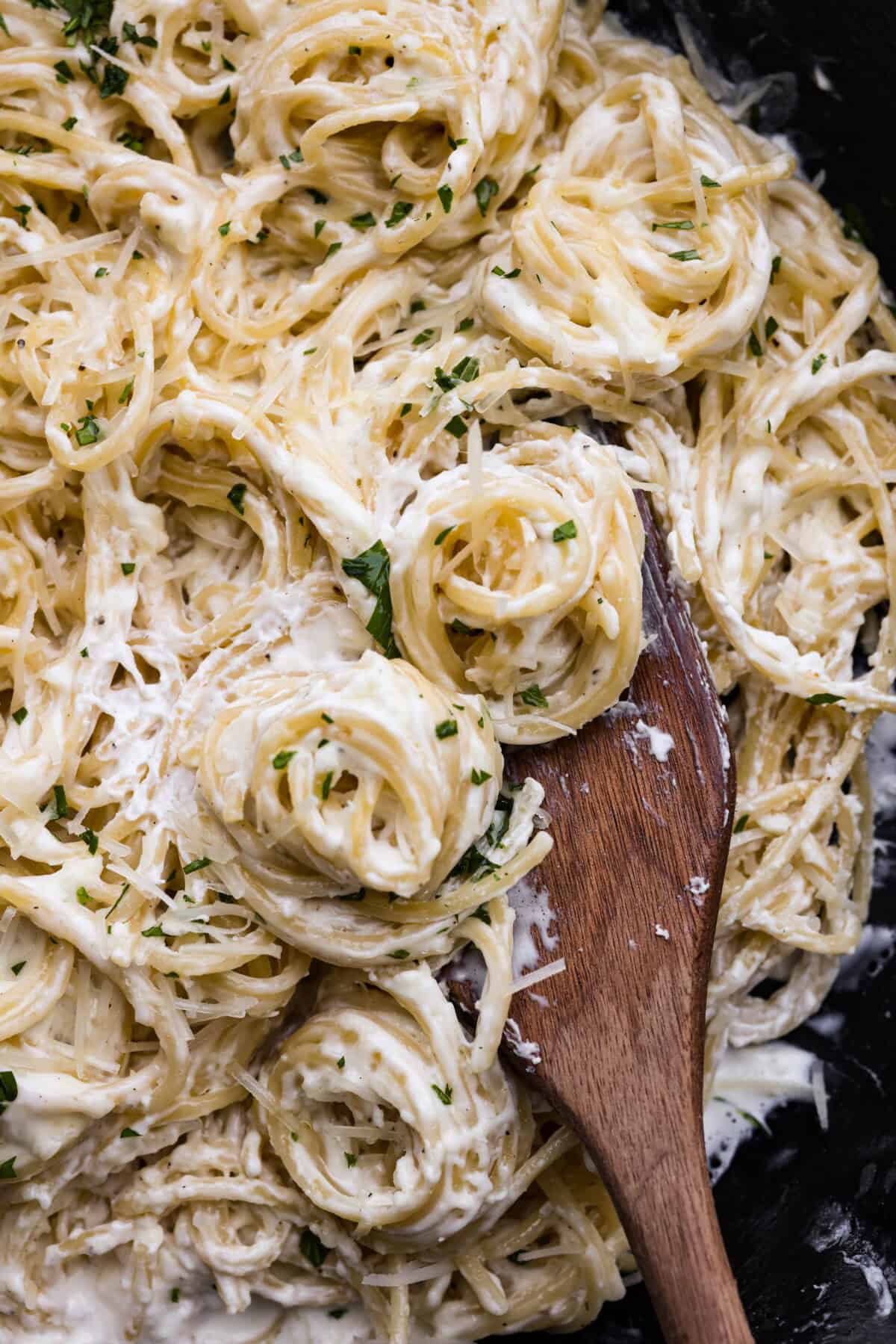 Close up shot of creamy parmesan pasta roni with a wooden serving spoon. 