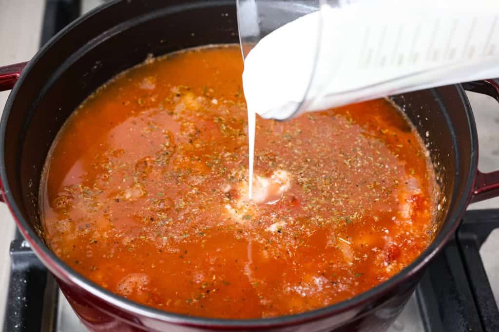 Overhead shot of heavy cream being poured in to the soup.