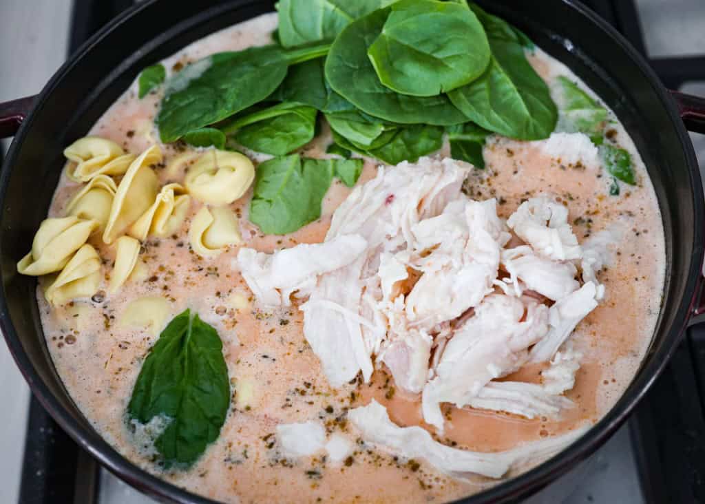 Overhead shot of the soup mix with heavy cream with added chicken spinach and tortellini.