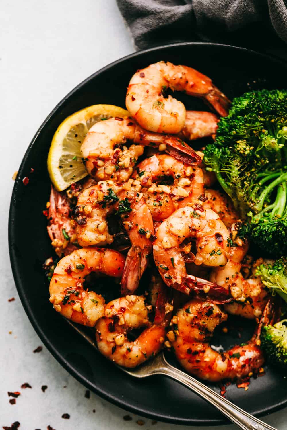 Brown Butter Spicy Garlic Shrimp on a black plate with broccoli.