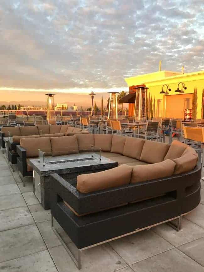 A photo with a couch on top of the roof top at the hotel with the sunrise. 