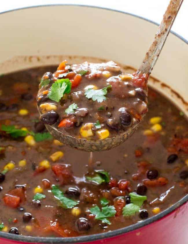 Black bean soup in a stew pot with a little scooping out the black bean soup.