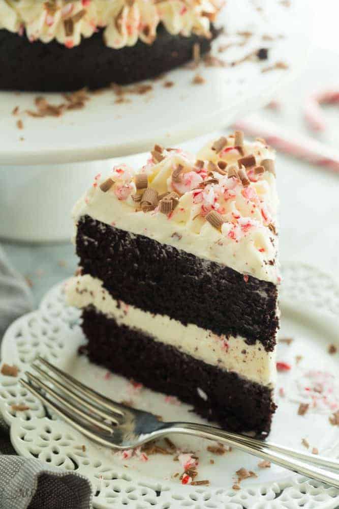 Ein Stück doppelter Schokoladen-Pfefferminz-Kuchen und ein weißer Teller mit einer Gabel daneben.