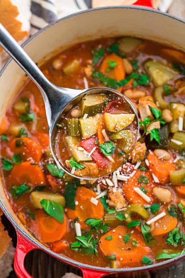 Tuscan vegetable chicken stew and a large pot with a little scooping up the soup. 
