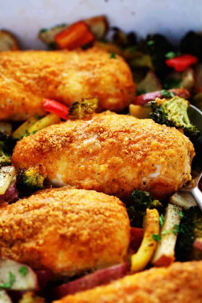 Crispy Parmesan paprika chicken laying on top of vegetables.