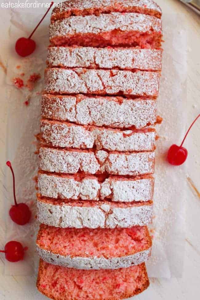 Overhead shot of cherry almond bread sliced into pieces with cherries on the side.