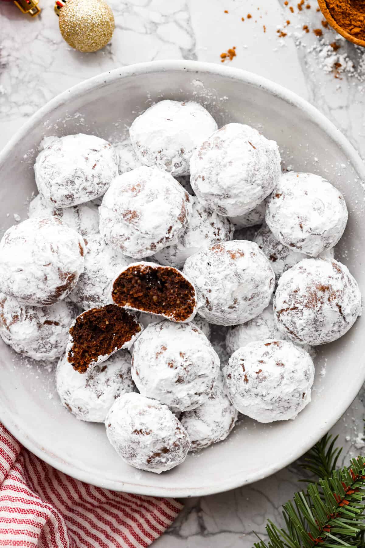 Top view of chocolate snowball cookies in a bowl.