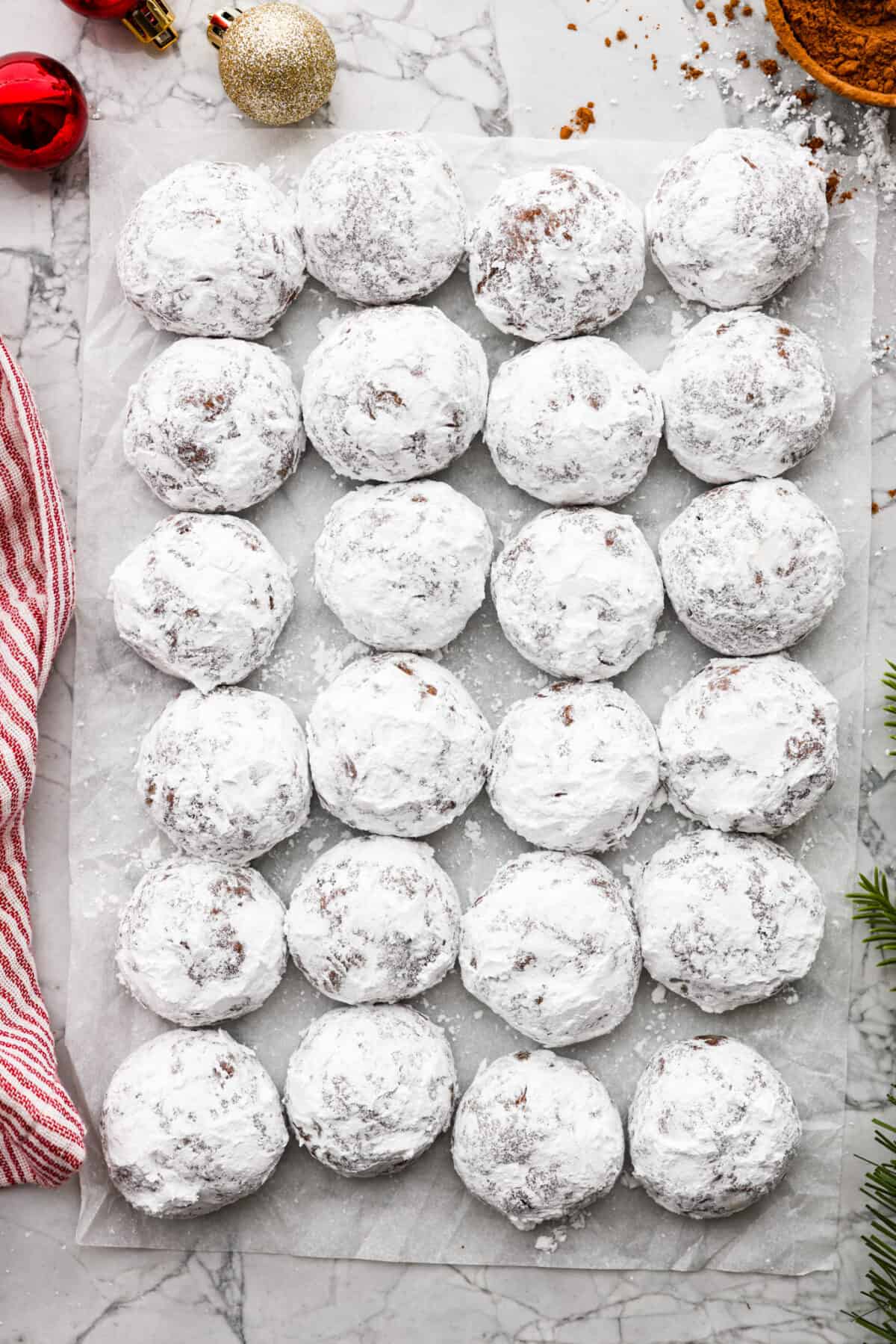 Top view of chocolate snowball cookies lined on parchment paper.